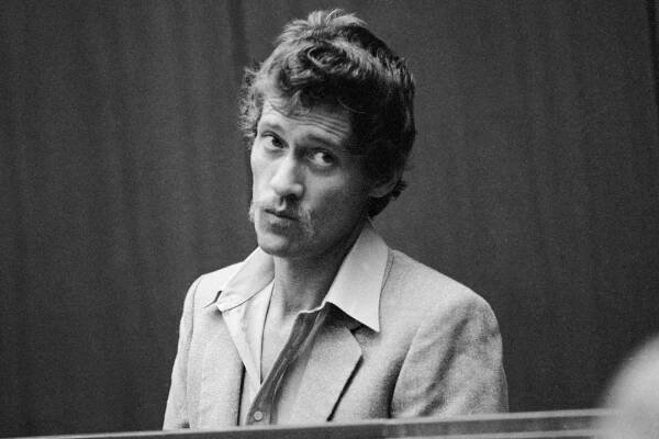 Porn star John Holmes= is charged with four counts of murder & one of attempted murder as he appeared in court 12/22, 