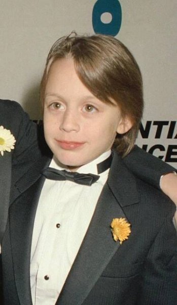 Two young actors in tuxedos, one pointing, at a formal event