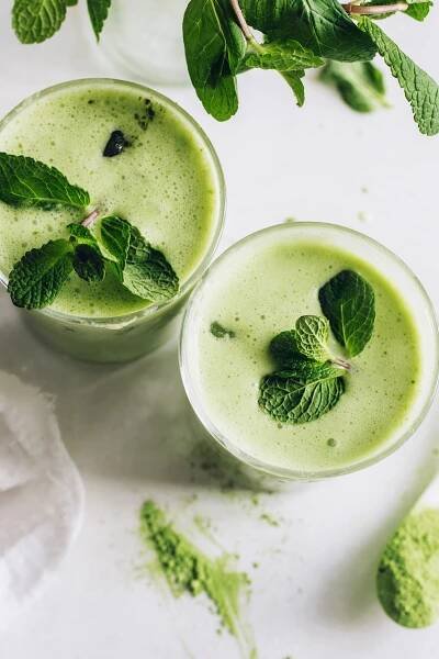 Top down shot of two glasses of frothy iced matcha lattes with fresh mint