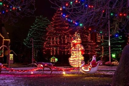 Santa v jeho saní, sobů a obří sněhulák a betlém jsou součástí slavnostní venkovní vánoční displeje na náves — Stock obrázek