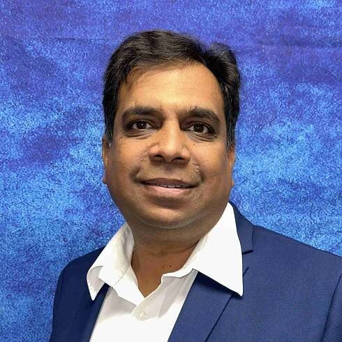 A man in a blue suit and white shirt poses against a blue textured background, looking directly at the camera, embodying career confidence.