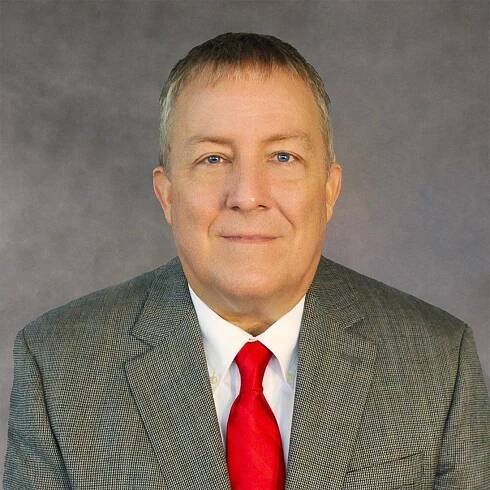 A man in a suit and tie is smiling for the camera