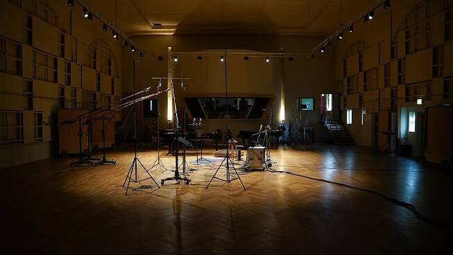 A spotlight illuminates some microphones at the center of a dark Teldex scoring stage