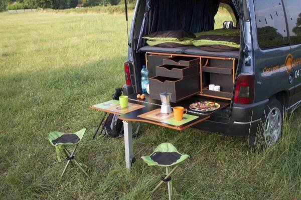 the van is parked in the grass with its door open and food on the table
