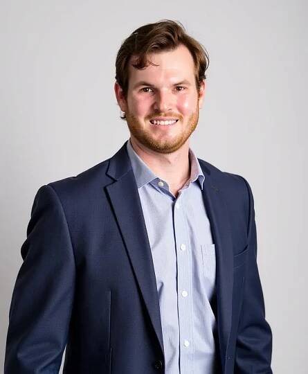 A man in a suit and shirt smiling for the camera.