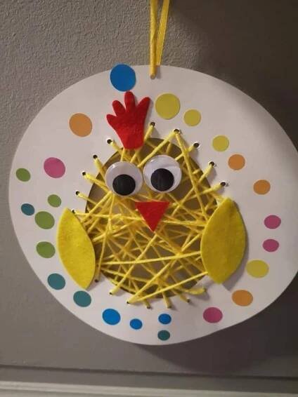 a paper plate with a bird made out of yarn and thread on top of it