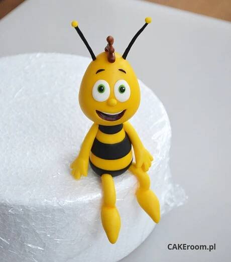 a yellow and black toy sitting on top of a white cake covered in frosting
