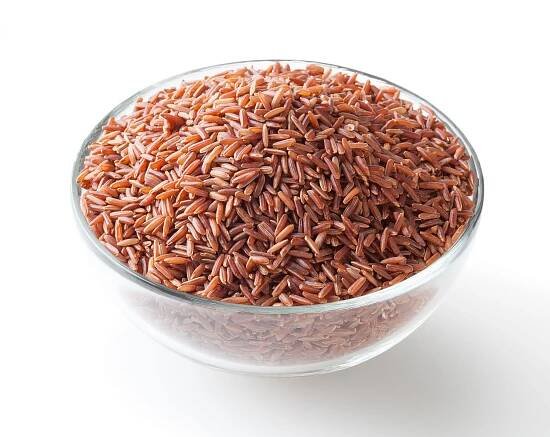 Uncooked red rice in glass bowl isolated on white background with clipping path