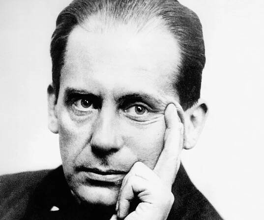 an old black and white photo of a man with his hand on his chin looking at the camera