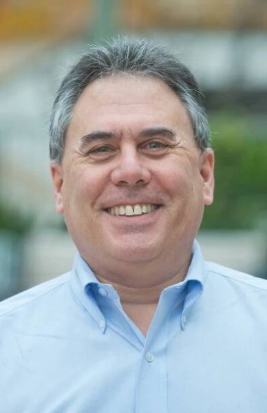 Jeff Levin smiles widely at the camera. He is a white man wearing a crisp blue button down shirt.