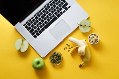Laptop a zdravé občerstvení na žlutém podkladu, koncept moderního životního stylu — Stock obrázek