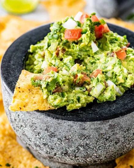 a bowl filled with guacamole and a tortilla chip in it