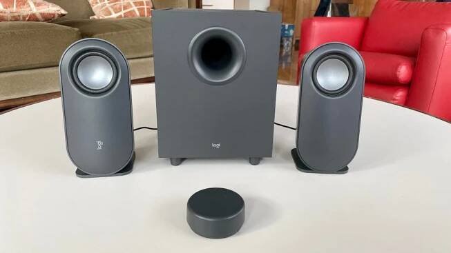 The grey Logitech z407 speakers set up on a white coffee table. 