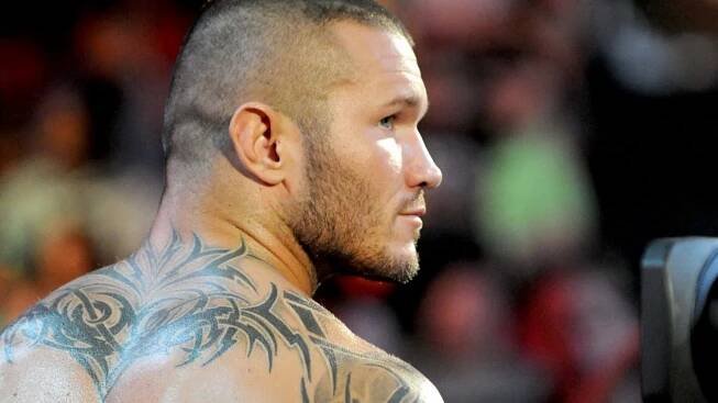 A Man With Tattoos On His Back Is Looking At The Camera Wallpaper