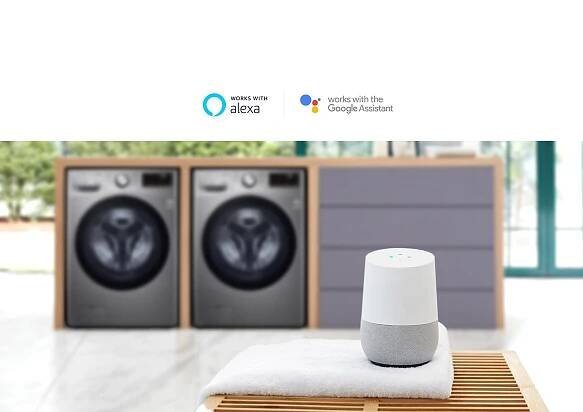 Background of the image is two washing machine front loading washers in a built in folding station slightly blurred with the LG ThinQ sitting on a towel on a table in the foreground.