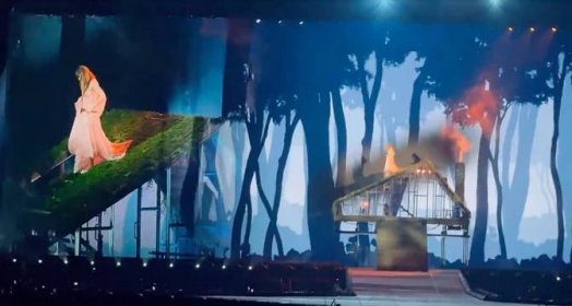 taylor swift's "folklore" concert set that features a burned-down house