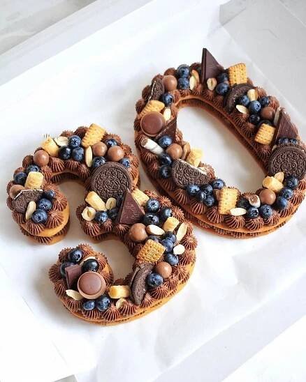two cookies shaped like the number 50 are decorated with chocolate, nuts and blueberries