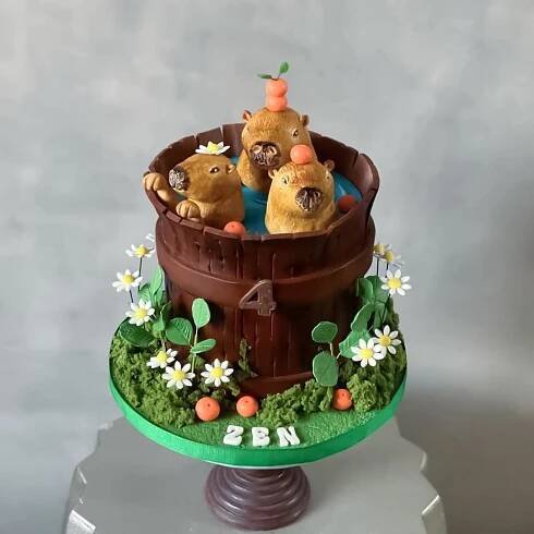 a cake made to look like three bears in a barrel with flowers and grass on top