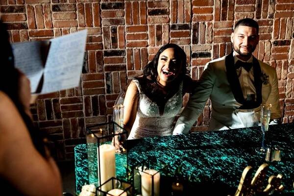 Photo of a bride and groom laughing during a bridesmaid speech during a reception at a The Vale Wedding in Conroe, Texas