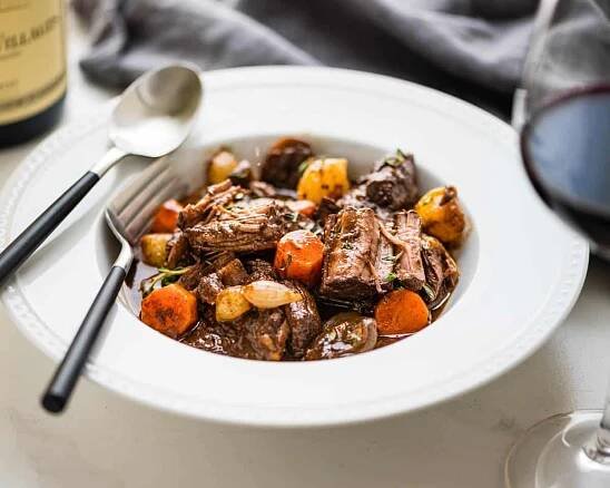 Serving beef bourguignon with red wine.