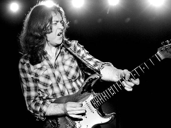 Rory Gallagher captured in black and white with his Stratocaster in hand.