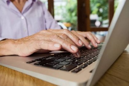 Seniorka/důchodkyně/žena u počítače, notebook, klávesnice, home office - ilustrační foto