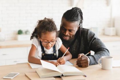 African-american father dad tutor childminder helping assisting with homework school project to a preteen daughter student. Homeschool concept. E-learning