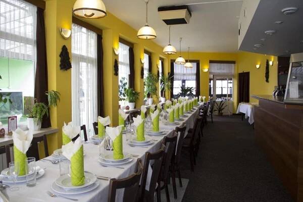 a long table with white tables and chairs in a restaurant at Penzion Oaza in Luhačovice