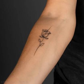 a woman's arm with a single flower tattoo on the left side of her arm