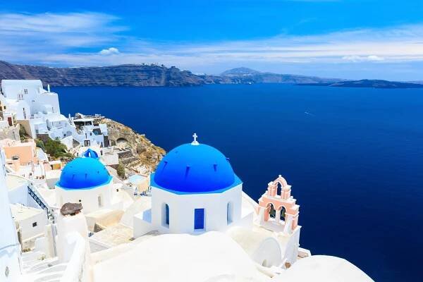 Santorini, Greece, with white buildings and blue-domed churches overlooking the Aegean Sea.