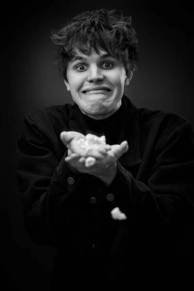 Portrait of crazy young man throwing up popcorn and grimacing . black and white — Stock obrázek
