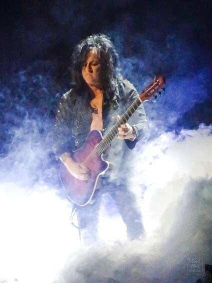 A photo of Steve Stevens playing a guitar while surrounded by special effects smoke at the Billy Idol concert. Rogers Place Edmonton Aug 1 2024