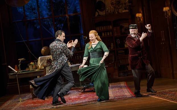 Actors performing a lively scene on stage, showcasing vibrant costumes and energetic choreography in a theatrical setting. The background features a vintage study filled with books and scientific instruments, enhancing the dramatic atmosphere.