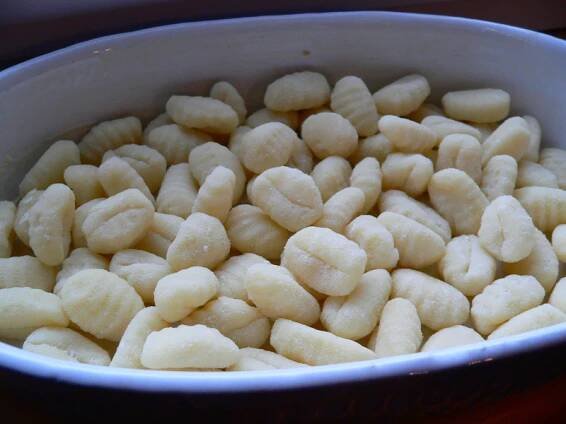 a white bowl filled with peeled bananas on top of a wooden table next to a knife