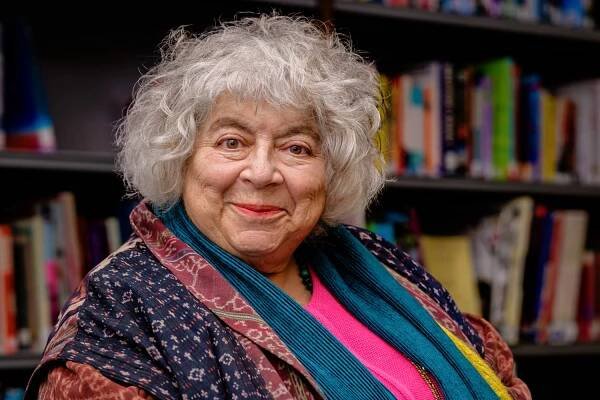 Miriam Margolyes smiling at camera in school library