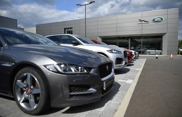a row of cars are parked in front of a land rover dealership