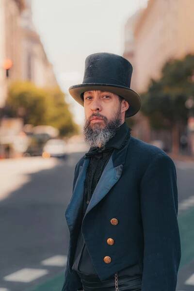 Free A vintage-clad gentleman with a top hat stands confidently on a city street. Elegant and historical attire. Stock Photo