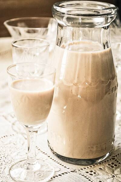homemade Irish Cream in a small bottle with cocktail glass.