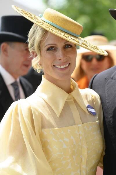 Zara Tindall smiling in yellow dress and matching hat at Ascot races