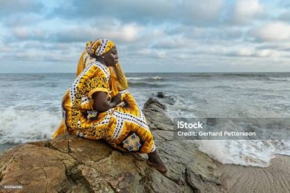 Africká žena s dlouhými šaty sedící na kamenném útesu - Bez autorských poplatků Ghana Stock fotka