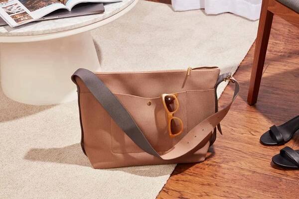 Cuyana Sling Bag resting on a carpet with shoes off to the side 