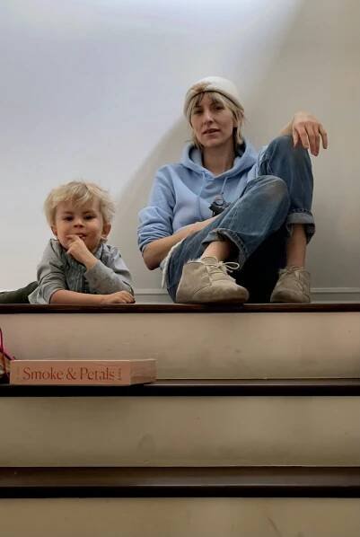 Mickey Sumner and her son, Akira, sitting on the floor at the top of a set of stairs 