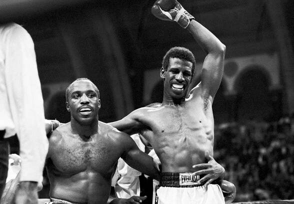 Michael Spinks raises his hand in victory after a boxing match.