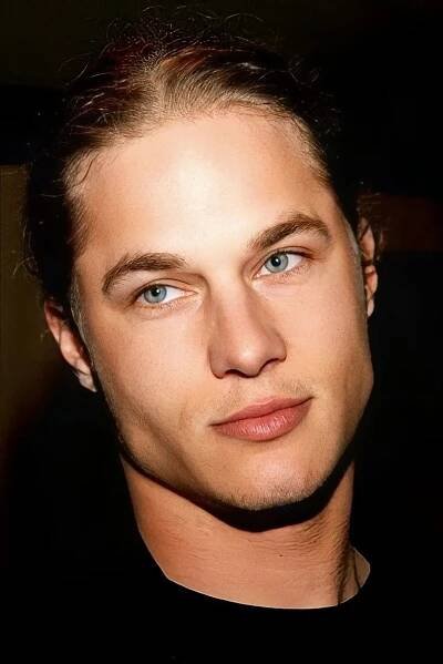 a close up of a person wearing a black shirt and looking at the camera with a serious look on his face