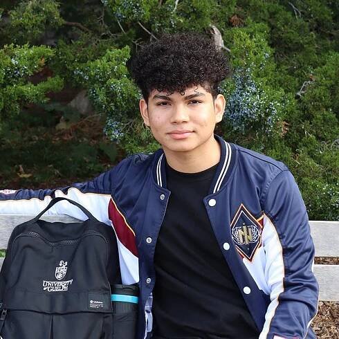 Young male Panamanian student sitting on a bench on campus.
