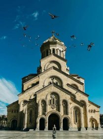 a large church with birds flying around it
