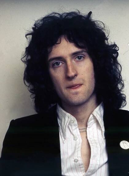 a man with long hair wearing a white shirt and black jacket