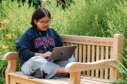 Student on laptop sitting on bench