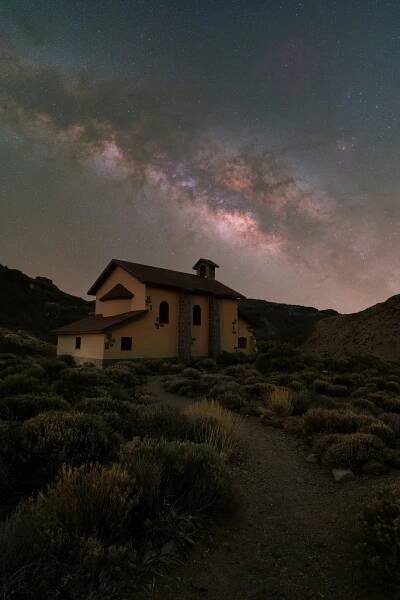 A church stands under a starry, milky way sky.