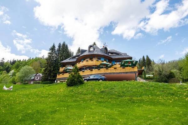 a large house on top of a green hill at Hotel Vladimír in Janske Lazne